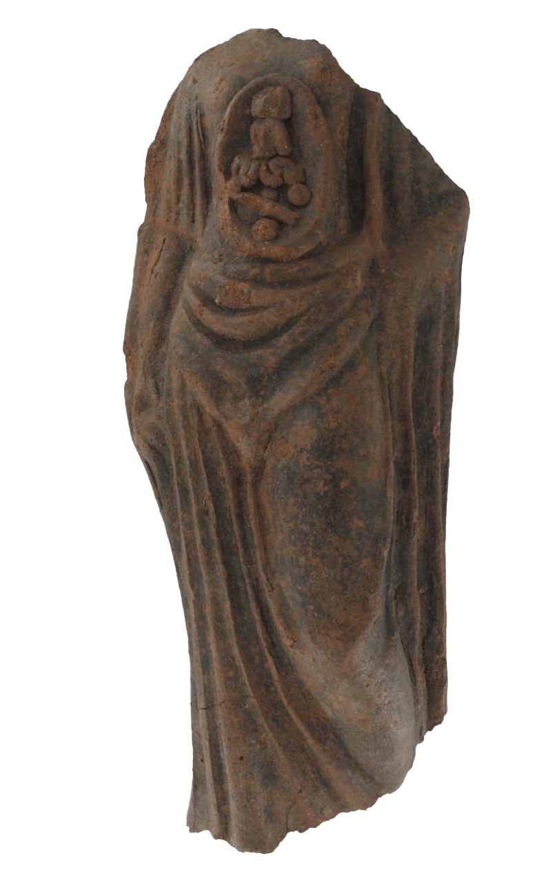 Eine weibliche Figur mit offenem Torso Die bräunlich-graue Statue ohne Kopf wurde 1885 in Mittelitalien, südöstlich von Rom ausgegraben. Sie stammt aus der Zeit zwischen dem 4. und 2. Jahrhundert vor Christus. Die Figur aus Terrakotta ist 26,5 Zentimeter hoch. Neben dem Kopf fehlen die linke Schulter und die Füße. Trotz des Verlustes dieser Körperteile lässt sich eine aufrechte Haltung erkennen. Die Frauengestalt scheint auf ihrem rechten Bein zu stehen, das linke ist etwas angewinkelt. Der rechte Arm hängt am Körper herab, vom linken ist der Unterarm erhalten, der in die Hüfte gestützt ist. Der Torso ist in ein fließendes knöchellanges Gewand gehüllt. An der Schulter, um die Hüften und zum Knöchel hin ist es üppig gefaltet. Der rechte Arm ist bis zum Ellenbogen bedeckt. Ein vertikal verlaufender ovaler Ausschnitt zieht sich vom Brustbein bis zur Scham. Darin sind die inneren Organe sichtbar. Ein senkrecht stehender Quader unterhalb des Brustbeins bezeichnet das Herz. Ein würfelförmiges Gebilde darunter stellt den Magen dar. An der breitesten Stelle, in der Mitte des Ausschnitts, befindet sich der waagerecht verlaufende Darm. Seine senkrecht angeordneten Schlingen füllen das gesamte Zentrum aus. Unterhalb des Darms liegen weitere Organe wie die Nieren. Die Statue war vermutlich eine Opfergabe, verbunden mit der Heilung erkrankter Organe oder stand im Zusammenhang mit dem Wunsch nach Fruchtbarkeit. — — A Female Figure with an Open Torso This brownish-grey statue without a head was excavated in 1885 in central Italy, southeast of Rome. It dates from the period between the 4th and 2nd centuries BC. The terracotta figure is 26.5 centimetres high. Besides the head, the left shoulder and the feet are also missing. Despite the loss of these body parts, an upright posture can be discerned. The female figure appears to be standing on her right leg and the left leg is slightly bent. The right arm hangs down the body, and the forearm of the left arm is preserved, supported on the hip. The torso is wrapped in a flowing ankle-length robe. It is luxuriantly folded at the shoulder, around the hips and towards the ankle. The right arm is covered up to the elbow. There is a vertical oval-shaped cutout that runs from the breastbone to the pubic region. The internal organs are visible within it. There is a vertically upright cuboid below the sternum indicating the heart. A cube-shaped structure below it indicates the stomach. There is a horizontally running intestine in the middle of the cutout at its widest point. Its vertically arranged loops fill the entire centre. Below the intestine are other organs such as the kidneys. It is probable that the statue was a votive offering associated with the healing of diseased organs or was related to the desire for fertility.